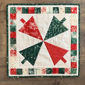 K&ouml;nnte beinhalten: Ein wei&szlig;er gesteppter Tischl&auml;ufer mit einem gr&uuml;nen und roten Weihnachtsbaumdesign. Der L&auml;ufer hat einen Rand aus gr&uuml;nen, roten und wei&szlig;en Stoffquadraten.