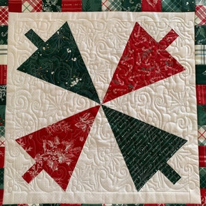 K&ouml;nnte beinhalten: Ein wei&szlig;er gesteppter Stoff mit einem roten und gr&uuml;nen Patchwork-Rand. Die Mitte des Stoffes zeigt vier rote und gr&uuml;ne Weihnachtsbaumformen, jede mit einem anderen Muster.