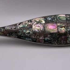 May include: A silver fish-shaped decorative object with a mosaic of iridescent abalone shell pieces.