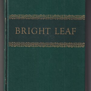 May include: A green hardcover book with gold lettering that reads "BRIGHT LEAF". The book has a decorative gold border design.