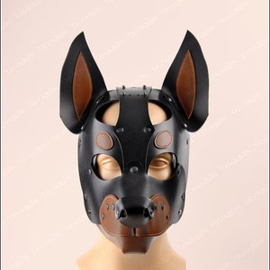 May include: A black leather dog mask with brown leather ears and nose. The mask has a studded design and is displayed on a mannequin.