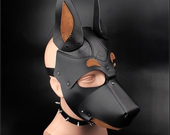 May include: Black leather dog mask with brown leather ears and nose. The mask has a studded collar and is worn on a mannequin head.
