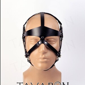 May include: Black leather head harness with a metal frame and straps. The harness has a blindfold and a nose piece.