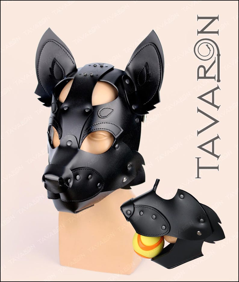 Puede incluir: Capucha de cachorro de cuero negro con orejas grandes y hocico, con detalles de remaches. Tambi&eacute;n se muestra una boquilla a juego m&aacute;s peque&ntilde;a con una pelota de tenis. La palabra "TAVARON" est&aacute; impresa verticalmente.