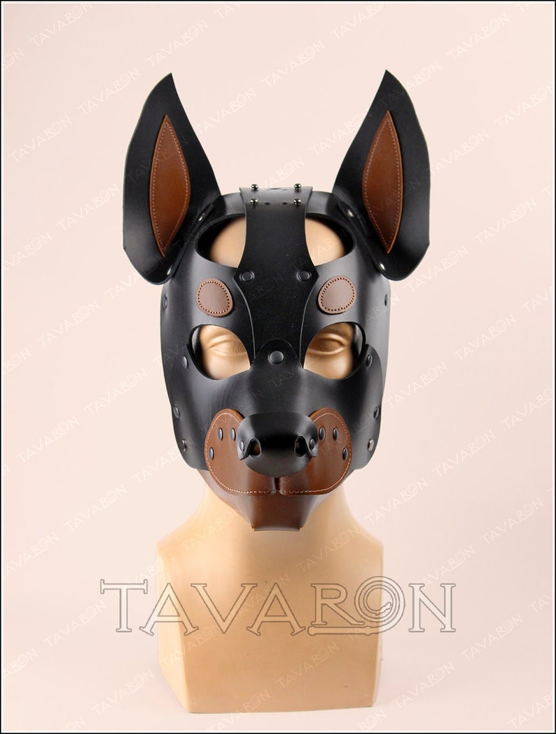 May include: A black leather dog mask with brown leather ears and nose. The mask has a studded design and is displayed on a mannequin.