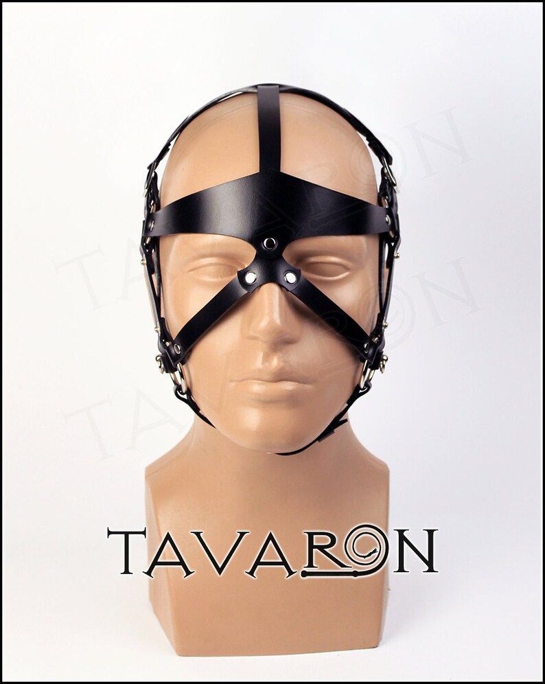 May include: Black leather head harness with a metal frame and straps. The harness has a blindfold and a nose piece.