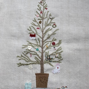 May include: A hand-stitched embroidered Christmas tree with a star on top, decorated with ornaments, a bird, a house, a stocking, a gift, and a wreath. The tree is in a brown pot with a heart design.