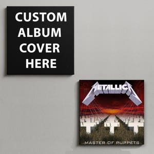 May include: Two square wall art canvases. The left canvas is black with the white text CUSTOM ALBUM COVER HERE. The right canvas features the Metallica Master of Puppets album cover art, showing white crosses in a field under a red sky.