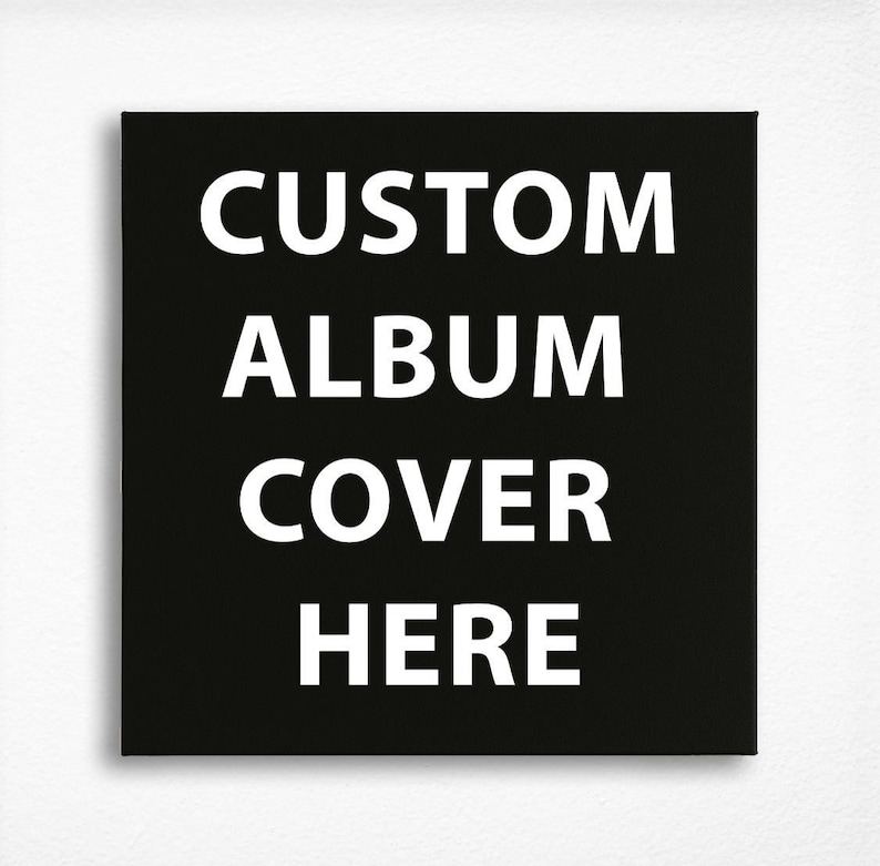 May include: A square black canvas print featuring the white text CUSTOM ALBUM COVER HERE centered in a bold, sans-serif font. The design is presented on a flat, solid black background, creating a high-contrast visual display for custom artwork.