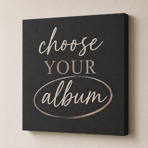 May include: A square black canvas wall art piece featuring the text choose YOUR album in a mix of script and serif fonts. The word choose is in a light script, YOUR is in a bold serif font, and album is in script inside a copper oval.