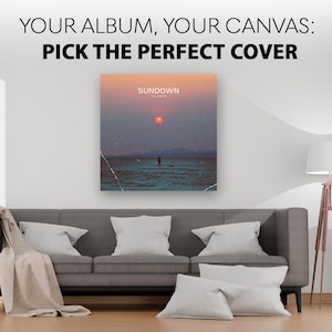May include: A square canvas print featuring a sunset over water with the text "SUNDOWN" and "ALBUM" displayed above a lone figure. The text "YOUR ALBUM, YOUR CANVAS: PICK THE PERFECT COVER" is printed in black above the centered wall art piece.