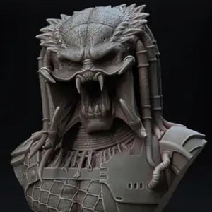 Peut inclure: Buste détaillé d'un extraterrestre Predator, avec une armure complexe et une expression menaçante. La sculpture est principalement grise, avec des dents acérées et des traits faciaux détaillés. Le buste est monté sur une base circulaire.