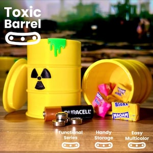 May include: A yellow toy barrel with a green dripping substance and a black radiation symbol. The barrel is open, revealing colorful sweets. A Duracell battery and small metal discs are in front. Text reads "Toxic Barrel".