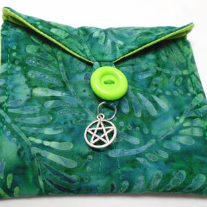 May include: A square, green fabric pouch with a batik pattern, a lime green button closure, and a silver pentacle charm. The pouch has a lime green trim and is likely used for small items or accessories.