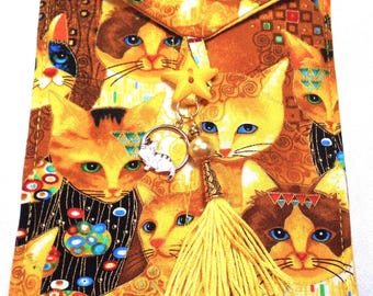 May include: A fabric clutch featuring a repeating pattern of stylized cats in shades of yellow, brown, and black. The clutch has a flap closure and is adorned with a yellow tassel and a charm with a cat design.