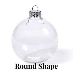 May include: A clear, spherical glass ornament featuring a silver-toned metal cap with a small wire loop for hanging. The ornament is transparent and smooth, with the text Round Shape printed in black letters at the bottom of the image.