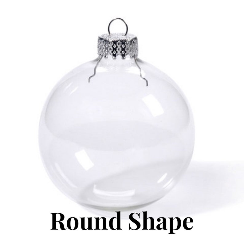 May include: A clear, spherical glass ornament featuring a silver-toned metal cap with a small wire loop for hanging. The ornament is transparent and smooth, with the text Round Shape printed in black letters at the bottom of the image.