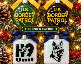 May include: Two round glittery ornaments in green and black featuring the yellow U.S. Border Patrol text and map outline, and two square iridescent glittery ornaments featuring black K9 Unit text with a badge and a German Shepherd dog graphic.