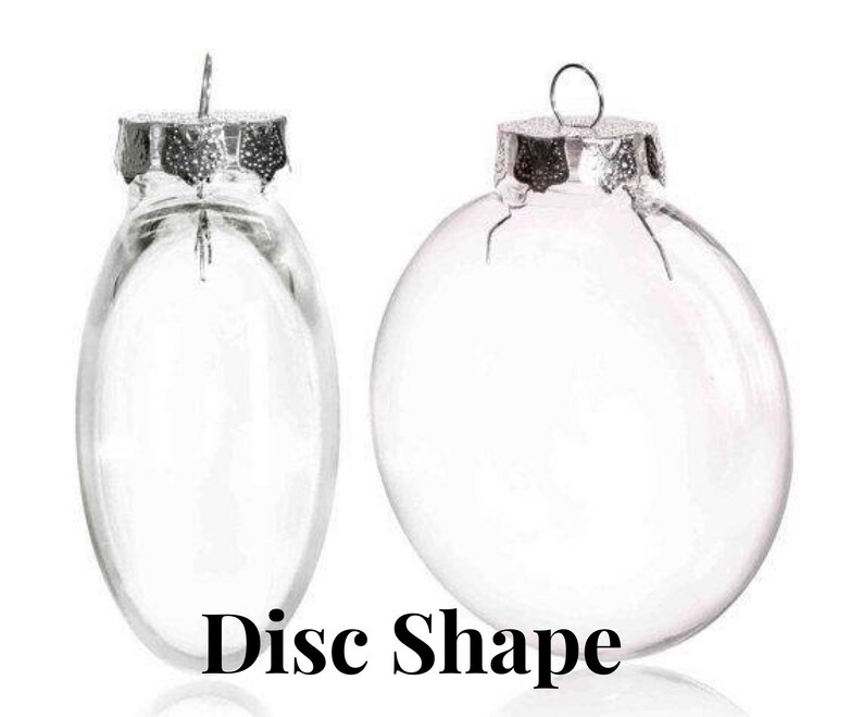 May include: Two clear glass disc-shaped ornaments with silver-colored metal caps and hanging loops. The text "Disc Shape" is printed in black at the bottom of the image. One ornament is oval, the other is round.