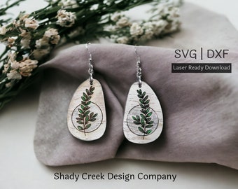 May include: A pair of wooden earrings with a green leaf design and a silver hook. The earrings are on a gray fabric background. SVG | DXF Laser Ready Download. Shady Creek Design Company.