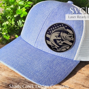 May include: A blue and white trucker hat with a round, laser-cut wood patch featuring a fish with an American flag design. The text "SVG|DXF Laser Ready Download" is visible in the top right corner of the image.