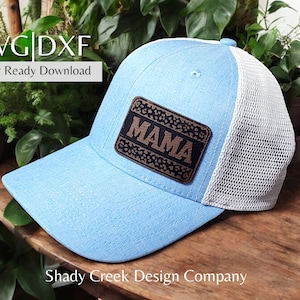 Könnte beinhalten: Ein hellblauer Trucker-Hut mit weißem Netzrücken. Der Hut hat einen braunen Leder-Patch mit dem Wort "MAMA" darauf.