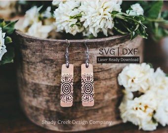 May include: A pair of wooden earrings with a geometric design. The earrings are laser cut and have a natural wood finish. The earrings are hanging from silver hooks. The image also includes the text "SVG | DXF Laser Ready Download".
