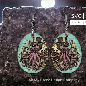 Peut inclure: Une paire de boucles d'oreilles en bois découpées au laser représentant un poulpe steampunk fantaisiste portant un chapeau haut de forme et des lunettes. Les boucles d'oreilles sont peintes dans des tons turquoise, rose, noir et or. L'image comprend le texte "SVG | DXF Laser Ready Download".