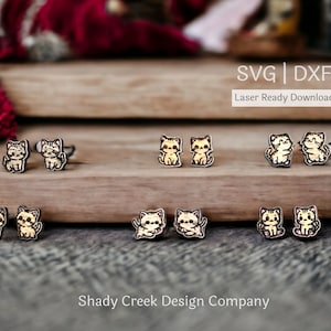Puede incluir: Seis pares de pendientes de madera cortados con láser que presentan un lindo diseño de gato de dibujos animados. Los pendientes son de madera clara con contornos negros. El texto "SVG | DXF Descarga lista para láser" es visible en la parte superior de la imagen.