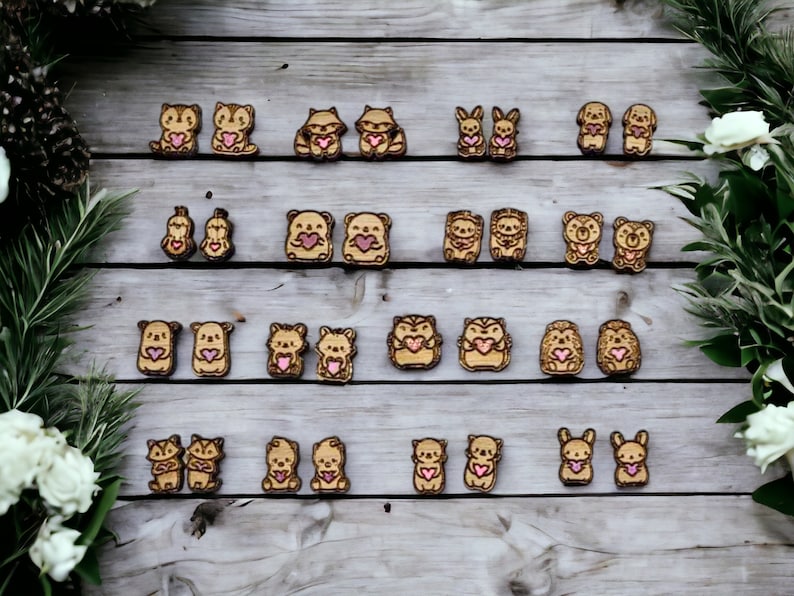 May include: A set of 20 wooden animal earrings with pink hearts. The earrings feature a variety of animals, including raccoons, bears, hedgehogs, bunnies, and foxes.