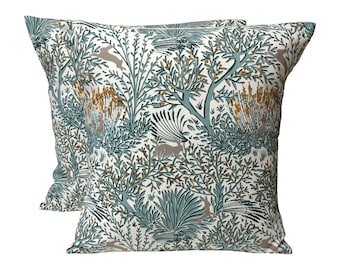 May include: Two decorative throw pillows with a white background and a teal and brown pattern of stylized trees, leaves, and rabbits.