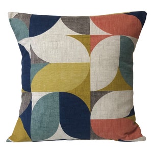 May include: A geometric patterned cushion with a cream background and colourful shapes in shades of blue, yellow, red, and green.