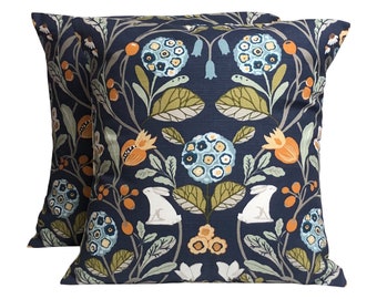 May include: Two navy blue throw pillows with a floral pattern featuring white rabbits, orange and yellow flowers, and green leaves.
