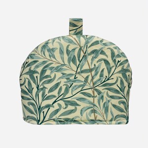 May include: A tea cosy with a handle, showcasing a repeating pattern of blue-green leaves and branches on a cream backdrop. The fabric tea cosy is designed to keep tea warm. The dome-shaped design is a classic.