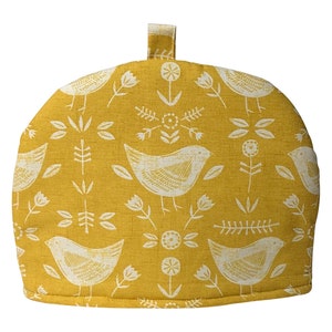 May include: A yellow tea cosy with a white bird and floral pattern.