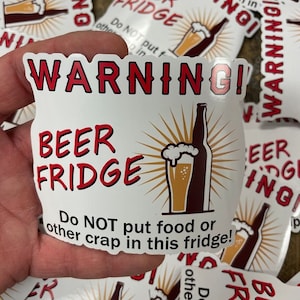 May include: White sticker with red text that reads "WARNING! BEER FRIDGE Do NOT put food or other crap in this fridge!"  A cartoon image of a beer bottle and glass of beer with a yellow sunburst behind it.