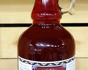 May include: A glass bottle with a red liquid inside. The bottle has a black cap and a handle. The label reads "Wild Huckleberry Margarita & Daiquiri Mix" and "Contains No Alcohol".