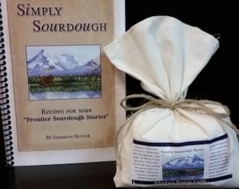May include: A white cloth bag tied with twine containing a sourdough starter. The bag is labeled "Frontier Sourdough Starter". A spiral bound book titled "Simply Sourdough" with the text "Recipes for your "Frontier Sourdough Starter" by Sharron Butler" is visible in the background.