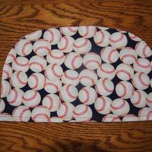 May include: A half-circle pot holder with a navy blue background and a pattern of white baseballs with red stitching.