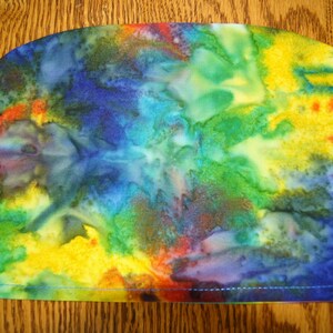 May include: A colorful tie-dye fabric with shades of blue, green, yellow, and red. The fabric has a smooth, soft texture and is perfect for crafting projects.