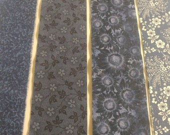 May include: Four fabric strips in shades of blue with different patterns. The first strip has a small, dark blue, floral pattern. The second strip has a larger, dark blue, floral pattern. The third strip has a large, dark blue, sunflower pattern. The fourth strip has a white floral pattern on a light blue background.