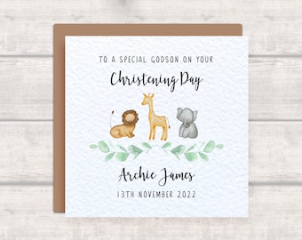 May include: A white card with a brown border. The card has a message that says "To a special godson on your Christening Day."  There are illustrations of a lion, giraffe, and elephant. The card also has the name "Archie James" and the date "13th November 2022".