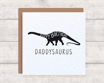 May include: A white card with a black dinosaur silhouette. The dinosaur's body is made up of the words "Happy Birthday". The text "Daddysaurus" is printed below the dinosaur.
