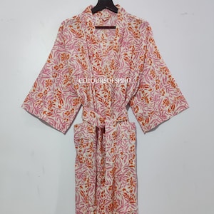 May include: A white cotton robe with a pink and orange floral print. The robe has a tie belt and two pockets.