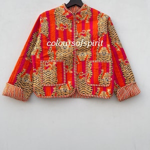 Pode incluir: Uma jaqueta acolchoada com gola mandarim e um padrão listrado em laranja e rosa. A jaqueta é coberta com um padrão repetido de tigres. O texto "coloursofspirit" é visível na frente da jaqueta.