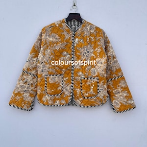 May include: A yellow quilted jacket with a floral print and black and white trim. The jacket has a stand-up collar and a zipper closure.