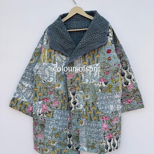 Könnte beinhalten: Gesteppte Jacke mit floralem Muster in Blau-, Rosa- und Gelbtönen. Die Jacke hat einen breiten Kragen und Dreiviertelärmel. Der Text "coloursofsprit" ist auf der Vorderseite der Jacke zu sehen.