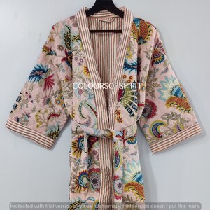 K&ouml;nnte beinhalten: Eine rosa gesteppte Robe mit Blumenmuster und gestreiftem Saum. Die Robe hat einen Bindeg&uuml;rtel und lange &Auml;rmel.
