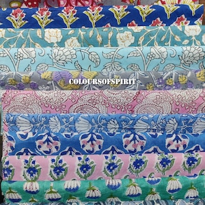 May include: A selection of folded fabric samples featuring floral designs in diverse colours. The fabrics include pink, red, blue, and green, with white and yellow accents. The text "COLOURSOFSPIRIT" is visible on one of the samples.