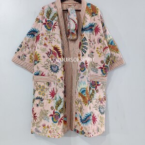 K&ouml;nnte beinhalten: Eine rosa-wei&szlig;e Baumwollrobe mit Blumenmuster und rot-wei&szlig;em Streifenbesatz. Die Robe hat eine passende Augenmaske.